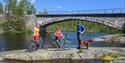 syklister tar en pause på en svaberg ved elva langs sykkelveien "gamle Treungenbanen"