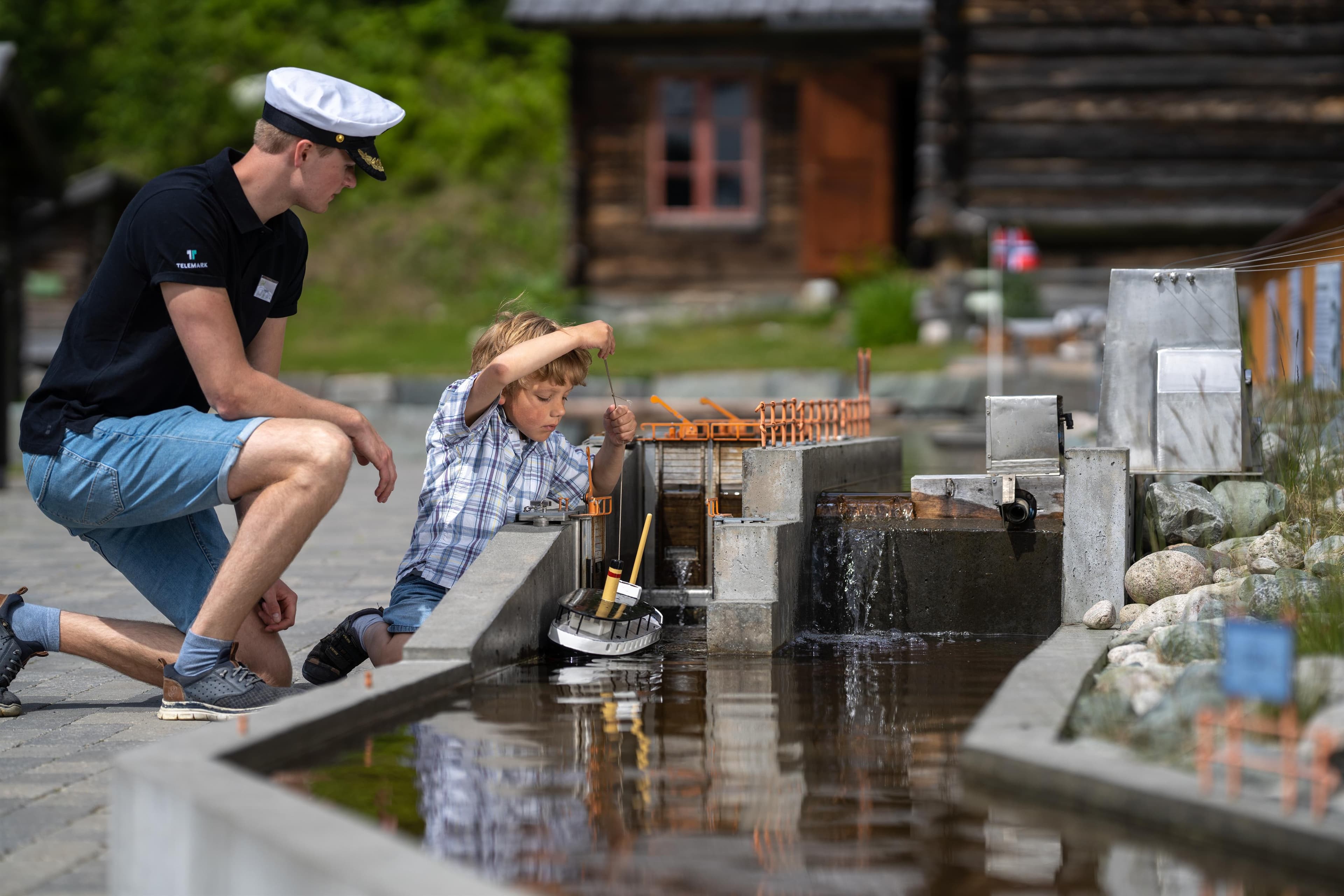 Slusevoktar og gutt slusar båtar i Telemarkskanalen på museet i Eidsborg.