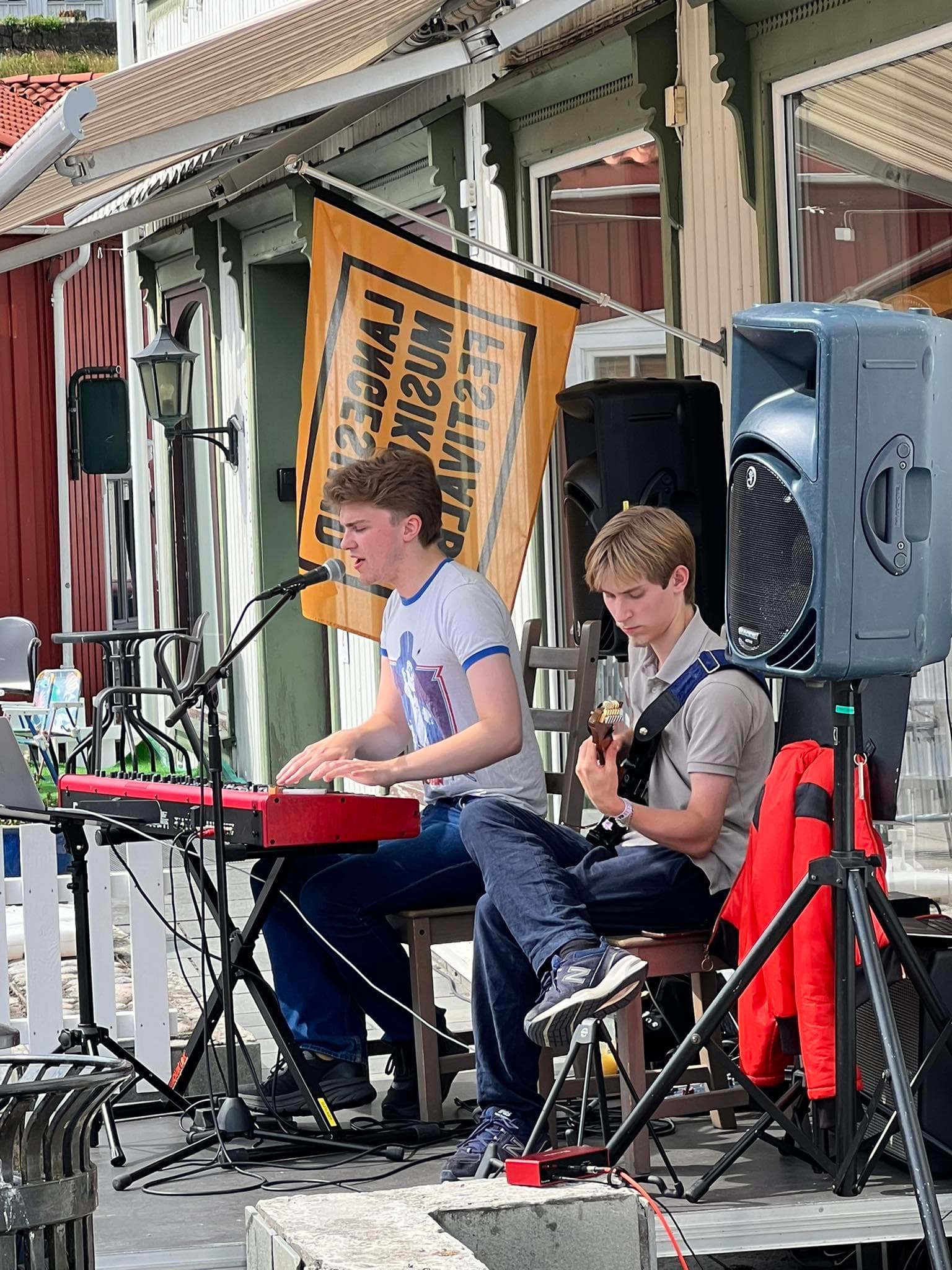 to gutter som spiller, en på rødt keyboard og en på gitar