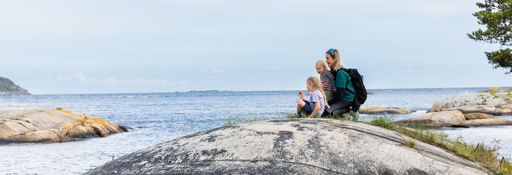 mor med barn som sitter på en svaberg på kyststien i Bamble