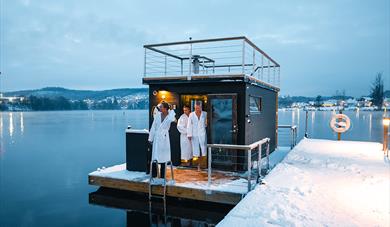 sauna på vannet med tre gjester i hvite badekåper