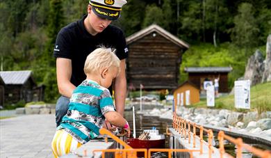 little boy locks a boat on the miniature version of the telemark canal in the canal park at Vest-Telemark Museum in Eidsborg 