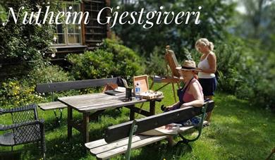 2 damer i en hage maler på lerret. KUNSTKURS uke 26 på Nutheim