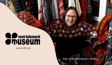 Strikkedesignar Irene Haugland omgjeve av fargerike plagg. Utstilling Vest-Telemark museum Eidsborg.