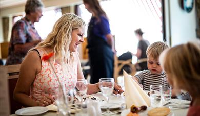 mor og barn sitter på restaurant på Straand Hotel