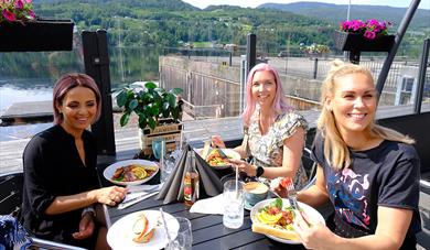 Tre kvinner spiser mat og koser seg på uteserveringen til Dany's Café i Bok & Blueshuset i Notodden. Foto