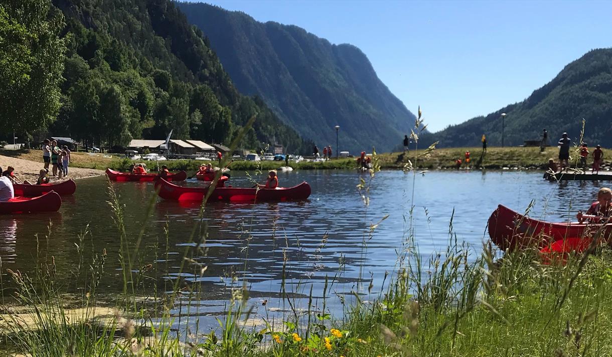 Badestrand med vann og høye fjell i bakgrunnen