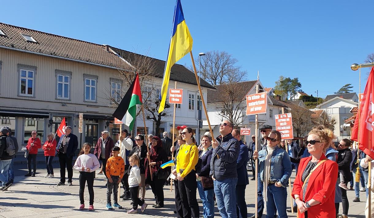 mennesker foran trehus med flagg