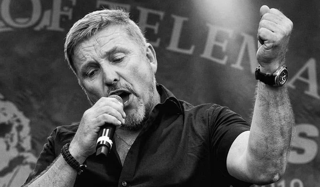 svart hvitt bilde av mann med mikrofon i sort kortermet skjorte