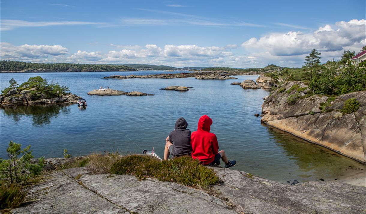 2 som sitter på en skjær og ser ut over vannet