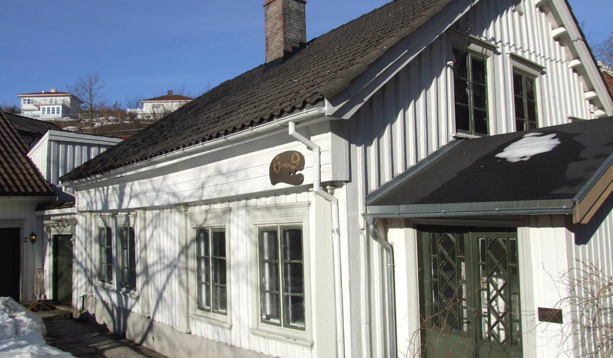 et hvitt gammelt trehus med grønne dører og vinduer