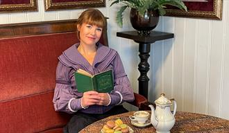 dame som leser en bok fra Henrik Ibsen i Ibsenstua på Brekkeparken i Skien