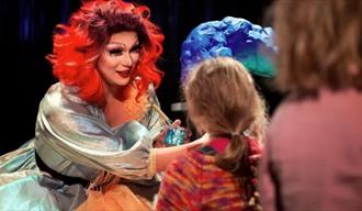 En dragqueen i rødt hår og sølvkjole