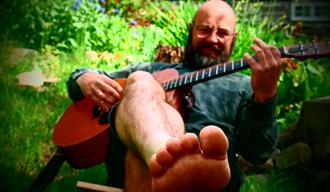 Ikke høgg ned treet; en mann som sitter med en gitar i en hage