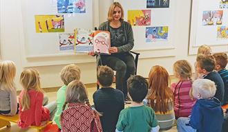 dame leser book til barn på bibliotek