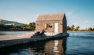 gutt hopper fra stupebrett foran den flytende badstuen i Langesund