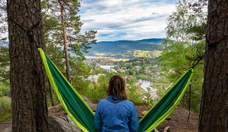 Kvinne i hengekøye som ser utover utsikten på Kåfjellåsen, i Notodden. Foto