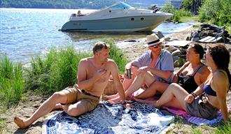Mennesker på stranden Linstå. Båt i bakgrunn. I Notodden. Foto