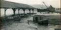 FLOM: Bildet er datert 21. august 1924, og det er flom i vassdraget. Tønner og andre varer flyter i det flomstore vannet.