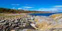 folk som går på rullesteinstrand på Jomfruland