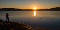 Fiske med stang på svaberg i solnedgang