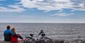 par sitter på rullesteinstrand på Jomfruland