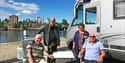 Bobilparkering i Skien. En gruppe eldre sitter ved siden av bobilen ved bobilparkering i Skien