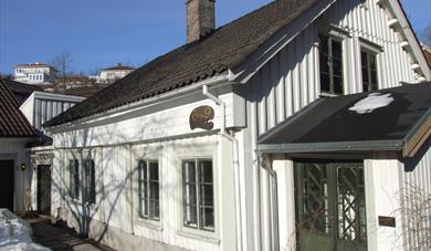 et hvitt gammelt trehus med grønne dører og vinduer