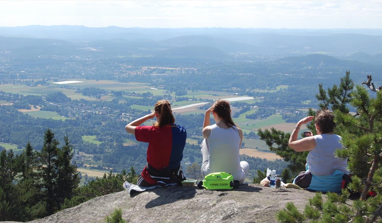 3 damer sitter på toppen av Skrehelle og nyter utsikten