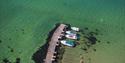 Rognsåsen kyststien Bamble utsikt over grønt vann og båter som ligger fortøyd ved en brygge