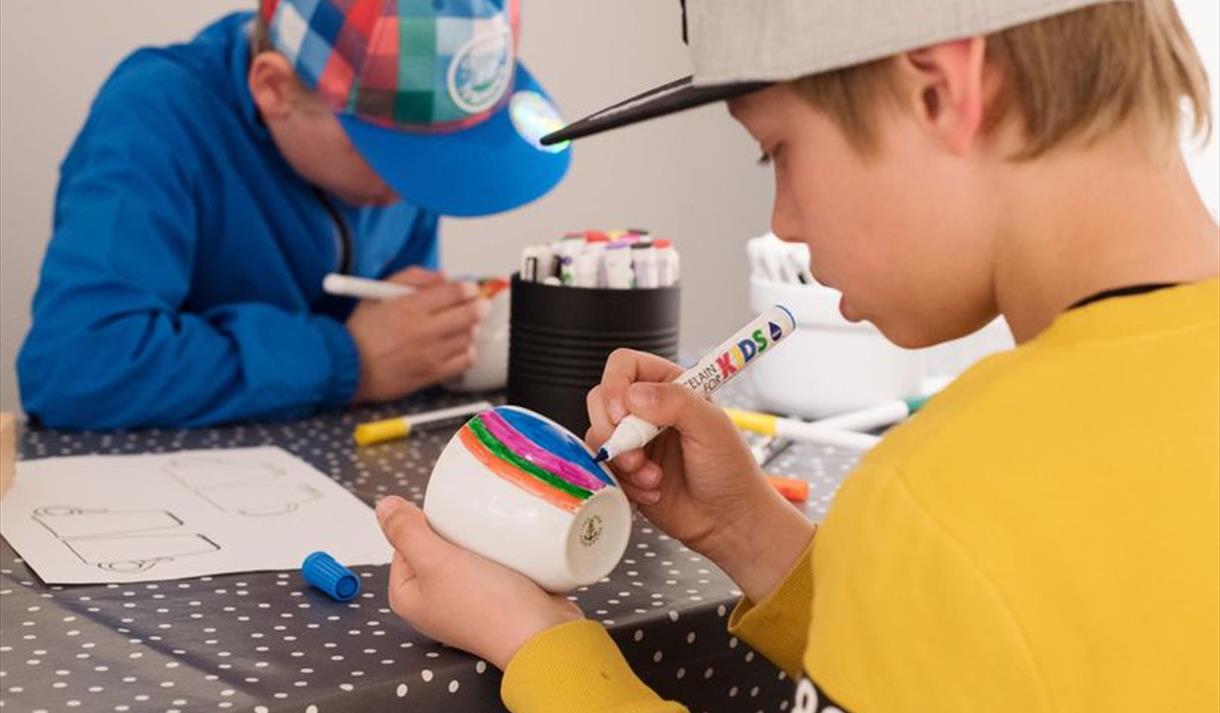 Hva skjer i Porsgrunn - barneverksted på Porselensmuseet. Bilde av 2 små gutter som dekorerer kopper