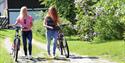2 jenter med sykler i folkestadbyen i Fyresdal