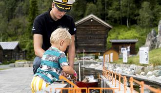 liten gutt sluser en båt på miniatyrutgaven av telemarkskanalen på kanalparken på Vest-Telemark Museum i Eidsborg